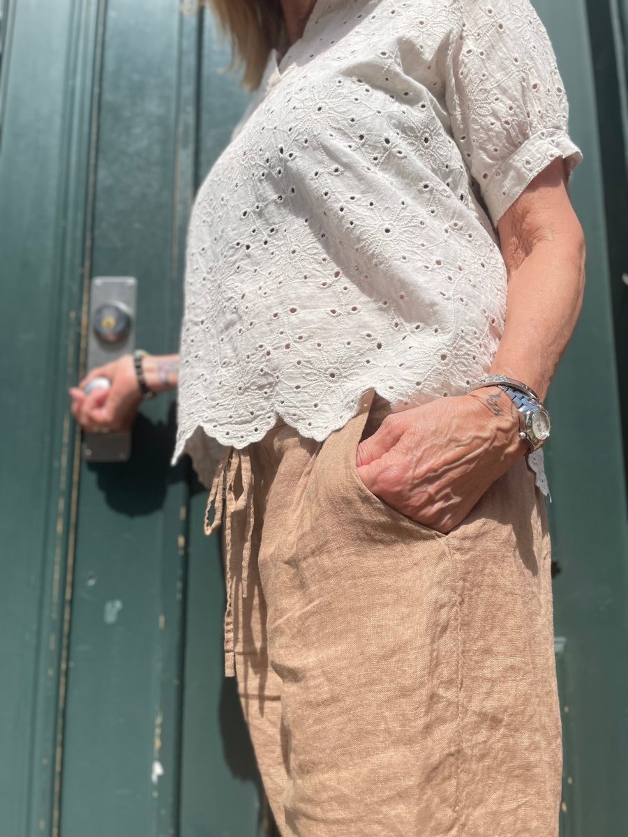 A woman in beige linen pants and white blouse outside a building